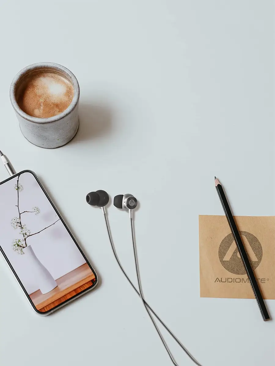 Composite product image of wired Bluetooth earbuds integrated into a lifestyle tabletop scene